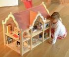 Девочка играет с куклой и кукольный дом с мебелью